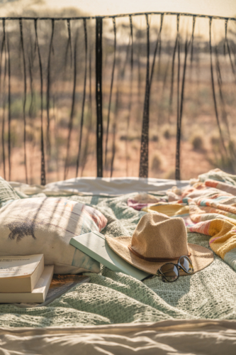 hat sunglasses and book laying on campervan bed in outback - Australian Stock Image