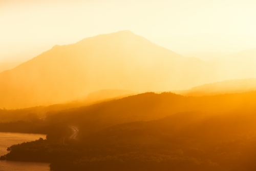 Hazy orange sunset over coastal highway and mountains