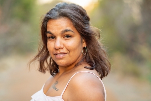 head and shoulders of young aboriginal woman outdoors with blurry background - Australian Stock Image