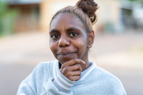 head and shoulders of young aboriginal woman with hand to chin - Australian Stock Image