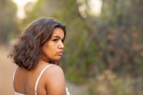 head and shoulders of young lady turning to look back over shoulder