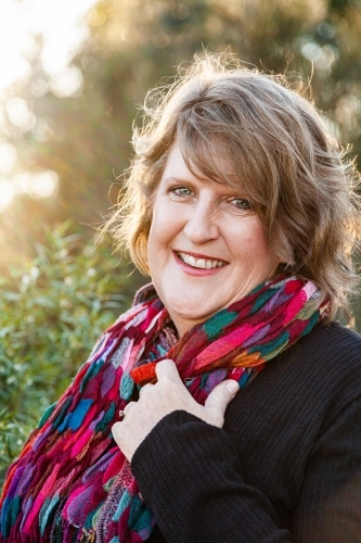Head and shoulders portrait of a happy middle aged woman with colourful scarf - Australian Stock Image