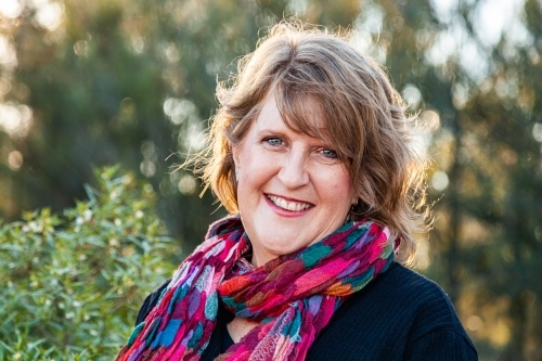Head and shoulders portrait of a happy middle aged woman with colourful scarf - Australian Stock Image