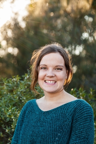 Head and shoulders portrait of a happy young woman with green background - Australian Stock Image