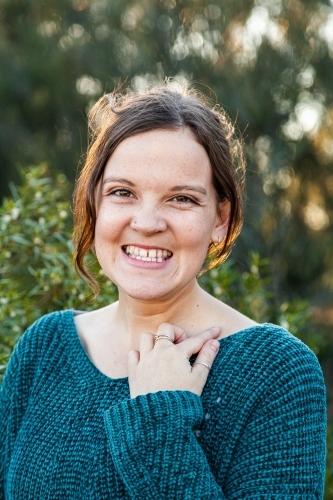 Head and shoulders portrait of a happy young woman with green background - Australian Stock Image