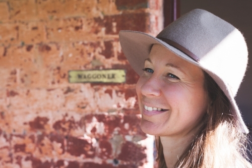 Head of woman smiling in front of rustic wall - Australian Stock Image