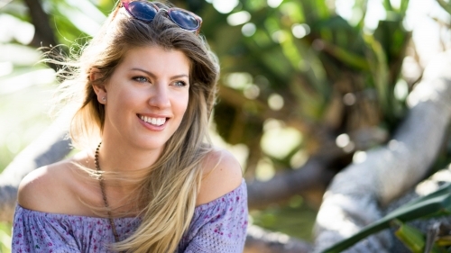 Headshot of woman with blonde hair wearing an off-shoulder top - Australian Stock Image