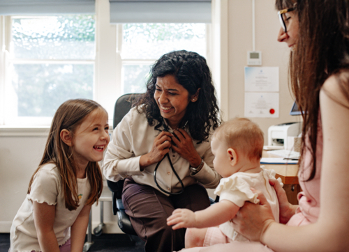 Healthcare professional meets with a parent and her kids during a clinic consultation - Australian Stock Image