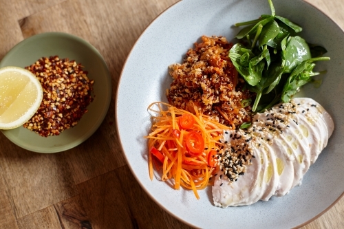 Healthy chicken and salad dish on wooden table in cafe - Australian Stock Image