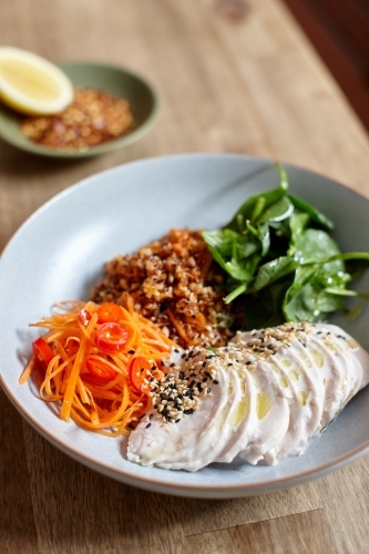 Healthy chicken and salad dish on wooden table in cafe - Australian Stock Image