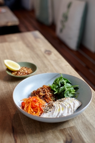 Healthy chicken and salad dish on wooden table in cafe - Australian Stock Image