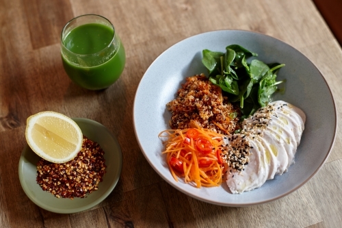 Healthy chicken and salad dish on wooden table in cafe - Australian Stock Image