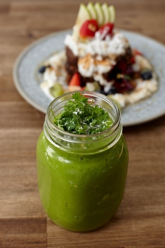 Healthy organic green smoothie drink on wooden table - Australian Stock Image