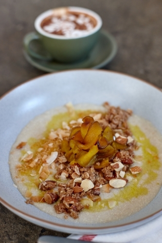 Healthy porridge served with hot beverage in vegetarian cafe - Australian Stock Image