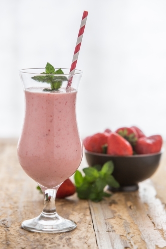 Healthy Strawberry Smoothie with straw and bowl of fresh strawberries - Australian Stock Image