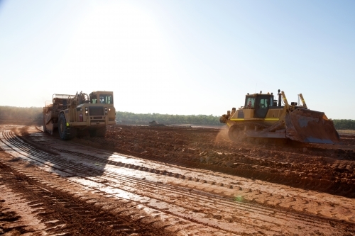 Heavy machinery flattening dirt to build a road - Australian Stock Image