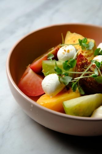 Heirloom tomatoes salad with mozzarella cheese in a pink bowl - Australian Stock Image