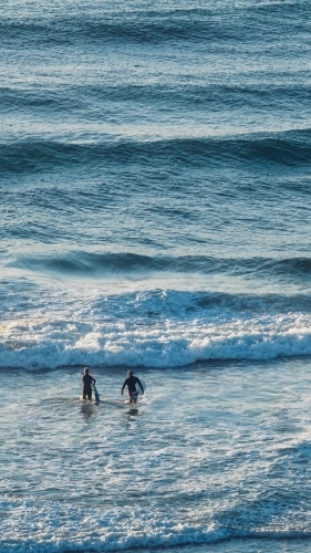High view of two surfers entering beach