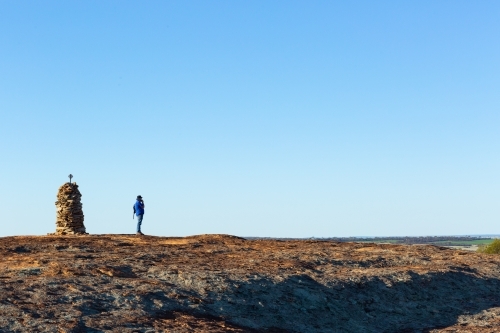 Hiker atop granite outcrop next to rock cairn - Australian Stock Image