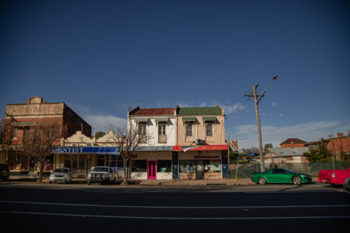 Historic Australian main street with vintage buildings and parked cars under a clear blue sky - Australian Stock Image