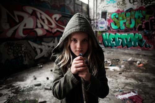 Hooded girl holding a pipe with attitude