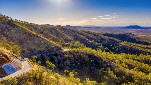 Horizontal photo of winding road in Mount Morgan with a steep road side with wild flowers and plants - Australian Stock Image