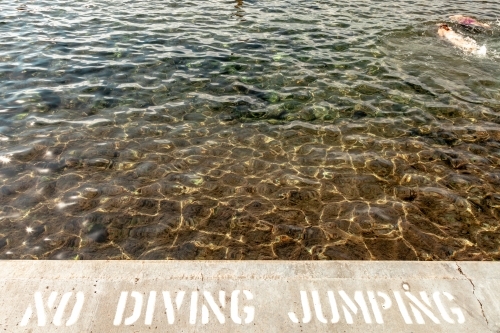 horizontal shot of a beach with a no diving and no jumping sign