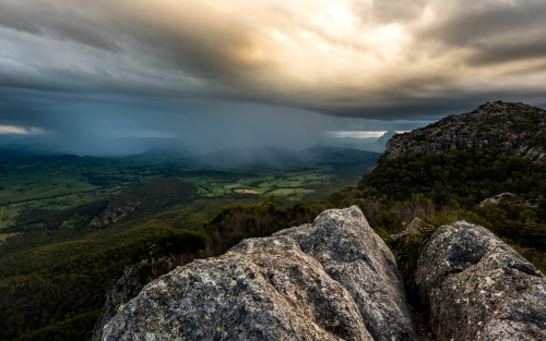Horizontal shot of a beautiful scene with mountains, high rocks, and forest at sunset - Australian Stock Image
