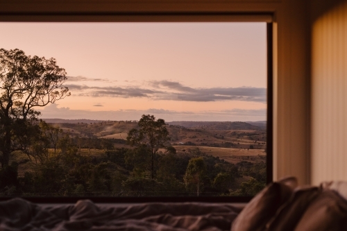 Horizontal shot of a bedside window with trees and mountain background