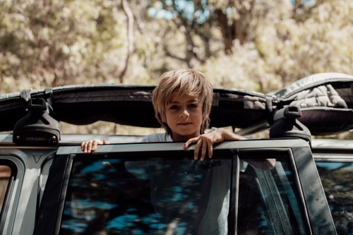Horizontal shot of a boy leaning on the car door - Australian Stock Image