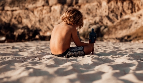 Horizontal shot of a boy playing with his toys in the sand - Australian Stock Image