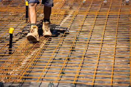 Horizontal shot of a builder walking on a reinforcement cage for concrete frame - Australian Stock Image