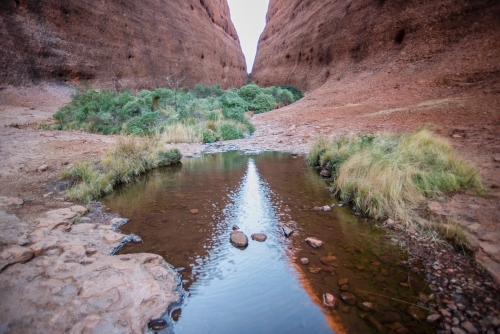 Horizontal shot of a creek with two large rock formation in the background - Australian Stock Image