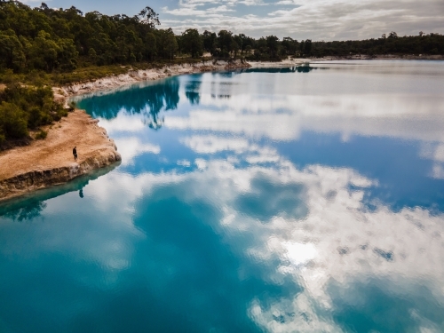 horizontal shot of a lake with sky reflection surrounded  by green trees - Australian Stock Image