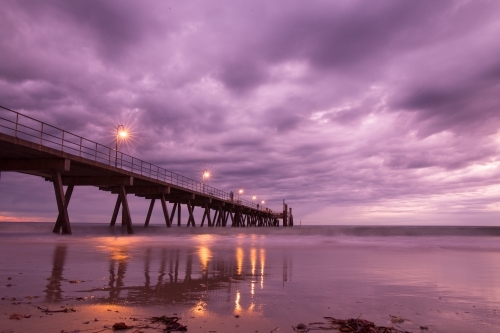 Horizontal shot of a long wharf on the beach at night time - Australian Stock Image