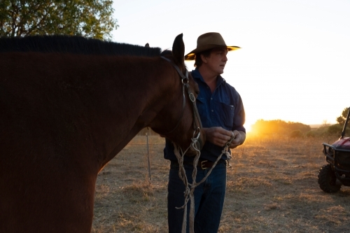 Horizontal shot of a man holding on the rope of his horse - Australian Stock Image