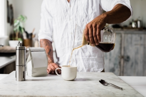 Horizontal shot of a man pouring coffee into  a cup - Australian Stock Image