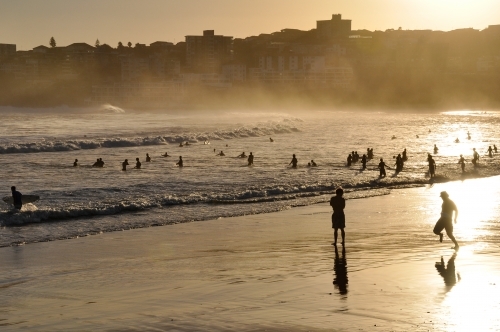 horizontal shot of a remote beach with people. mountains, rocks and waves with sunset - Australian Stock Image