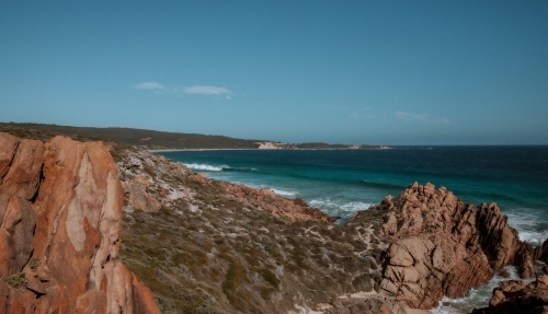 Horizontal shot of a rocky seashore under a blue sky