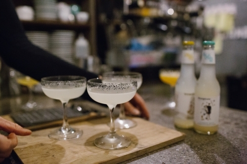 Horizontal shot of a server's hand serving a tray of cocktails. - Australian Stock Image
