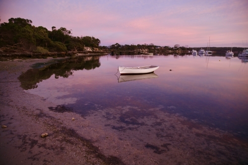 small boat on beach at low tide - Australian Stock Image
