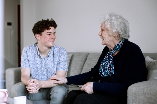 Horizontal shot of a teenage boy and and old woman talking - Australian Stock Image