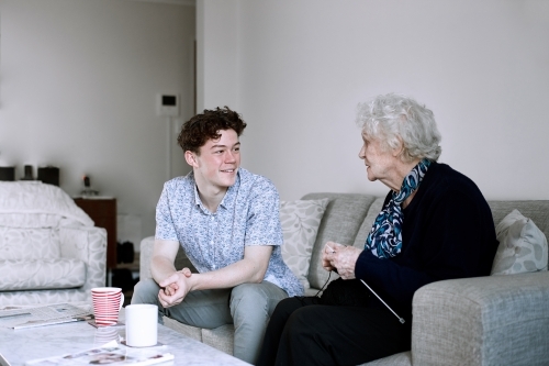 Horizontal shot of a teenage boy and and old woman talking - Australian Stock Image