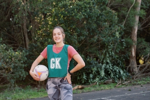 horizontal shot of a young woman in sports wear holding a net ball with other hand against her hips - Australian Stock Image