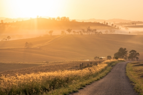 Horizontal shot of an empty road heading toward hills at dawn - Australian Stock Image