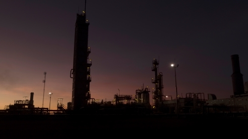 Horizontal shot of an industrial plant approaching sunrise/sunset - Australian Stock Image