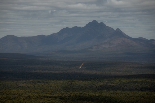 horizontal shot of an outback with grass, bushes, and mountain on a gloomy day - Australian Stock Image