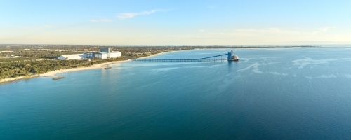 Kwinana grain terminal on a sunny day with white sand shoreline, bushes, trees and port - Australian Stock Image