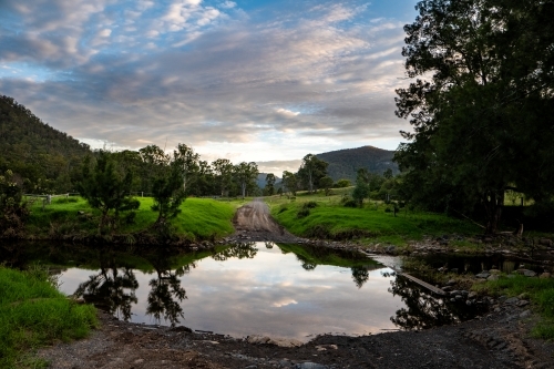 Horizontal shot of green trees near a lake under a cloudy blue sky - Australian Stock Image