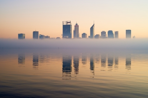 horizontal shot of Perth skyline at dawn with buildings reflected on misty water